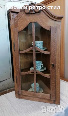 Красива ъглова витрина  от дърво, с декоративна дърворезба в горната част.