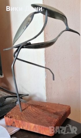 метална скулптура птичка на дървена основа